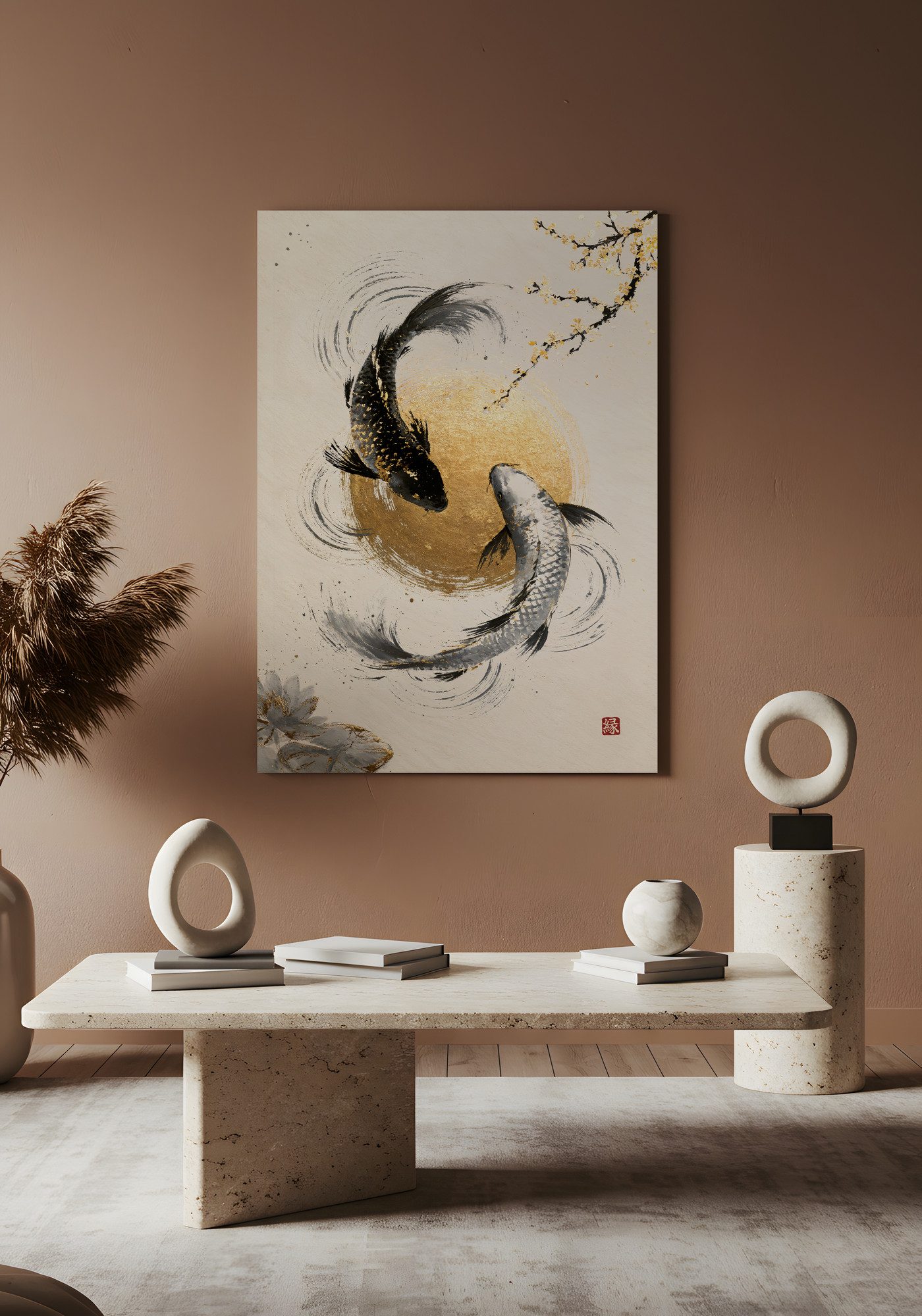 Koi Spirits of Moon and Sea: two koi circle a round gold disc, one dark and flecked with gold, one pale silver. Rings spread through the water around them, a branch with golden blossoms reaches in from the upper right, and a pale lotus sits in the lower left corner. A red seal sits in the lower right. The print hangs on a warm clay-colored wall above a low stone table. White ring sculptures, a round vase and small stacks of books stand on the table and on a stone pedestal at the right, and dried pampas grass rises on the left.